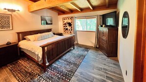 A bedroom with a wooden ceiling, a bed, a dresser, a TV, and a window with curtains. - Tahoe Living at the Forest’s Edge - 2BR + Loft, Near Heavenly & Beaches (South Lake Tahoe)