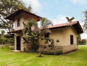 A two-story house with a brick facade, a tiled roof, and a small garden area with various plants.
