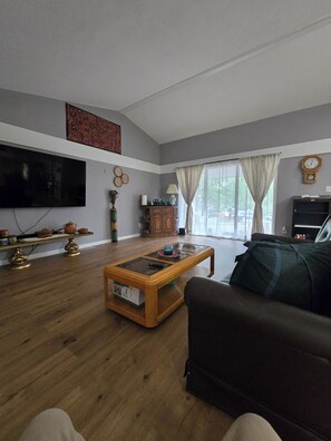 A living room with a flat-screen TV, a coffee table, a sofa, and a cabinet.