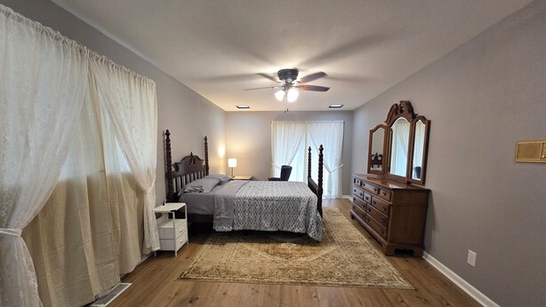 A bedroom with a bed, bedside table, dresser, mirror, ceiling fan, and a window with curtains. - Charming Blue Horizen 4-bedroom house with AC in quite neighborhood in Malvern (Malvern)