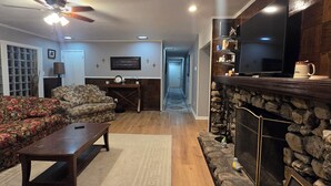 A living room with a fireplace, a sofa, a coffee table, and a television. - Charming Blue Horizen 4-bedroom house with AC in quite neighborhood in Malvern (Malvern)