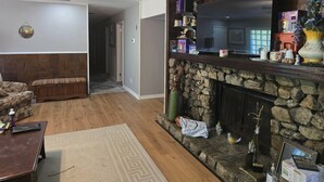 A living room with a stone fireplace, a television, and various decorative items. - Charming Blue Horizen 4-bedroom house with AC in quite neighborhood in Malvern (Malvern)