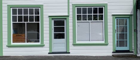 Un edificio con tres ventanas, cada una enmarcada en verde.