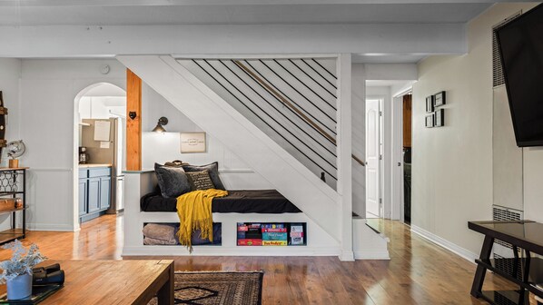 A modern living room with a staircase, wooden flooring, a sofa with cushions, and a coffee table.