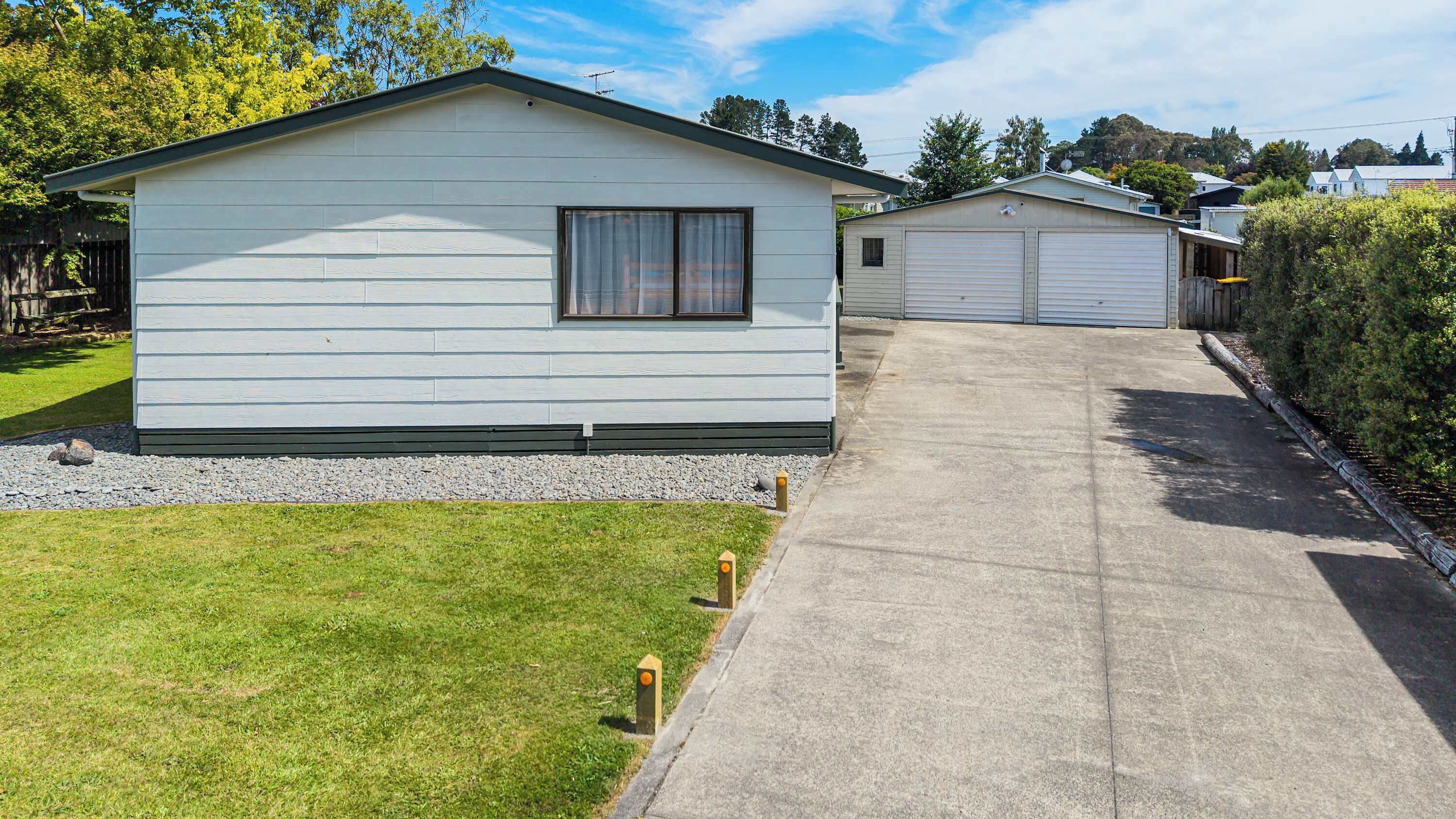 A row of single-story mobile homes with a paved driveway and a grassy lawn.