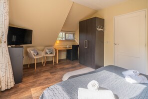 Ein Schlafzimmer mit zwei Betten, einem Schreibtisch, einem Fernseher und einem Kleiderschrank.
