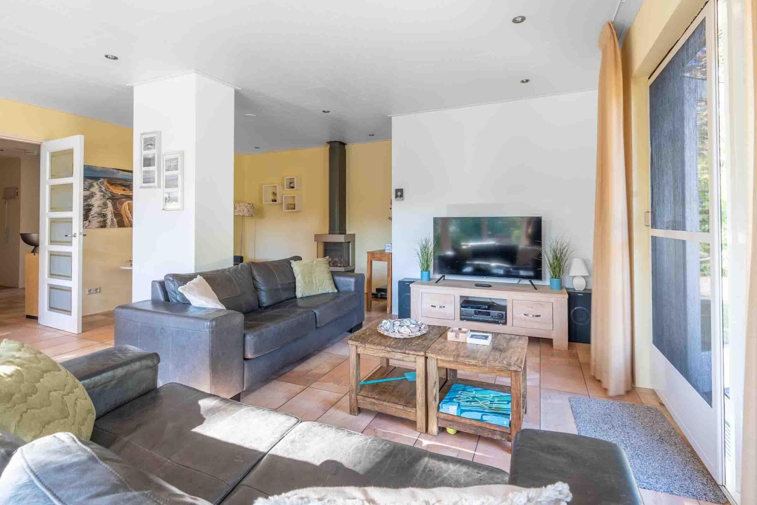 Een woonkamer met een bank, een salontafel, een televisie en een open haard.