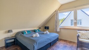 A bedroom with a bed, a nightstand, a lamp, a window with curtains, and a view of the outside. - Very Tastefully Furnished Country House for 4 People (Den Burg)