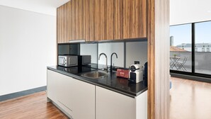 A modern kitchen with a wooden panel backsplash, stainless steel appliances, and a large window offering a view of the cityscape. - GuestReady - Ideal Porto stay near Trindade 4th (Porto)