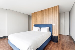 Ein modernes Hotelzimmer mit einem großen Bett, einer Wand aus Holzpaneelen und einem kleinen Beistelltisch.