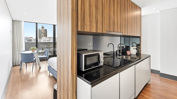 A modern kitchen with a microwave, sink, and wooden paneling. - GuestReady - Ideal Porto stay near Trindade 4th (Porto)