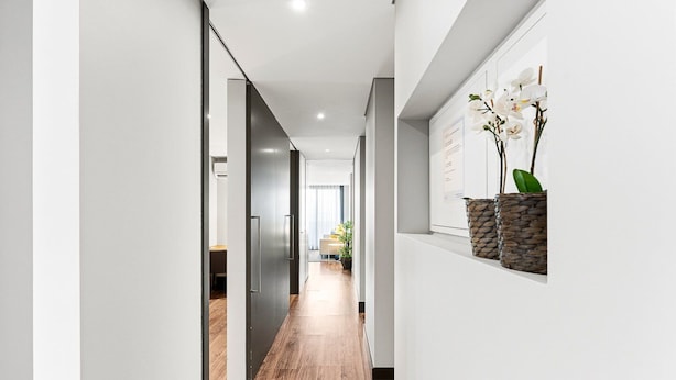 A modern hallway with a wooden floor, a glass door leading to a room, and a wall-mounted shelf with a plant. - GuestReady - Ideal Porto stay near Trindade GF-B (Porto)