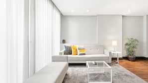 A modern living room with a grey sofa, a glass coffee table, a small side table with a lamp, and a potted plant. - GuestReady - Ideal Porto stay near Trindade GF-B (Porto)