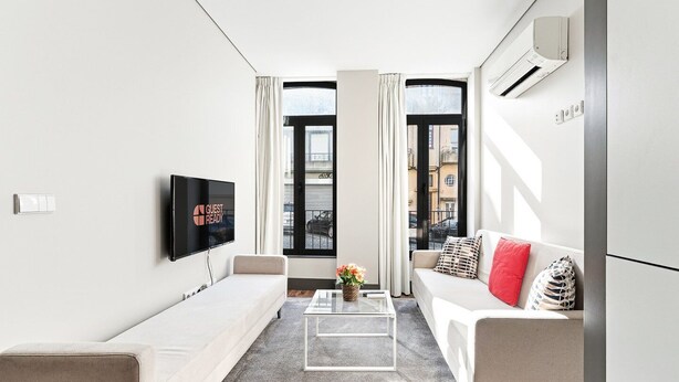 A modern, well-lit living room with a flat-screen TV, two sofas, a coffee table, and a large window with curtains. - GuestReady - Ideal Porto stay near Trindade GF-F (Porto)