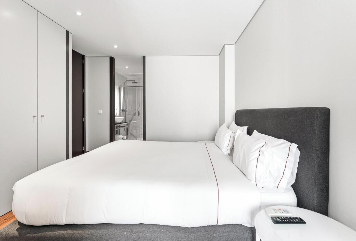 Ein modernes Hotelzimmer mit einem großen Bett, einem Nachttisch und einem Kleiderschrank.