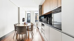A modern kitchen with a black countertop, wooden cabinets, and a dining area with a round table and chairs. - GuestReady - Ideal Porto stay near Trindade GF-F (Porto)