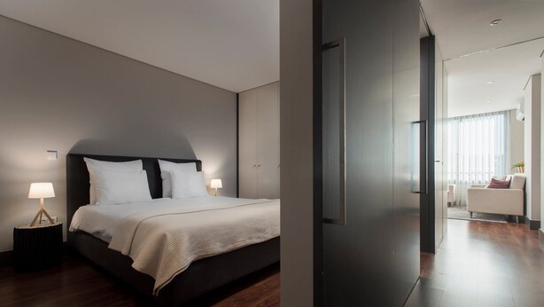 A modern bedroom with a large bed, bedside lamps, and a dark headboard. - GuestReady - Ideal Porto stay near Trindade 2nd (Porto)