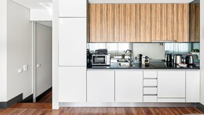 A modern kitchen with white cabinetry, a wooden upper cabinet, and a black countertop. - GuestReady - Ideal Porto stay near Trindade 2nd (Porto)