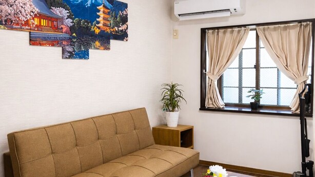 Un salón con sofá, una mesa de centro, una planta en maceta y una ventana con cortinas.