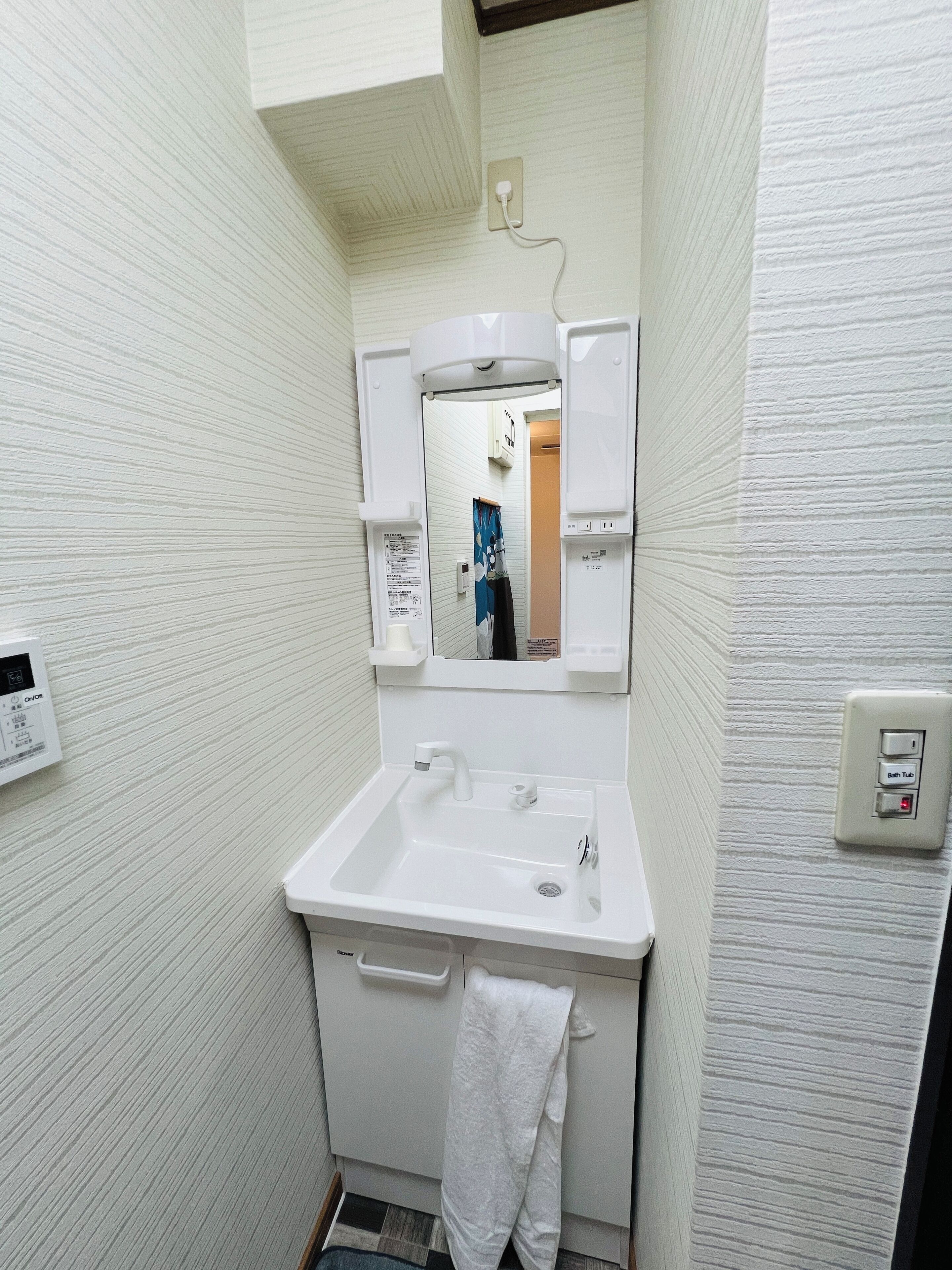 Une petite salle de bain avec un lavabo blanc, un miroir et une serviette accrochée au mur.