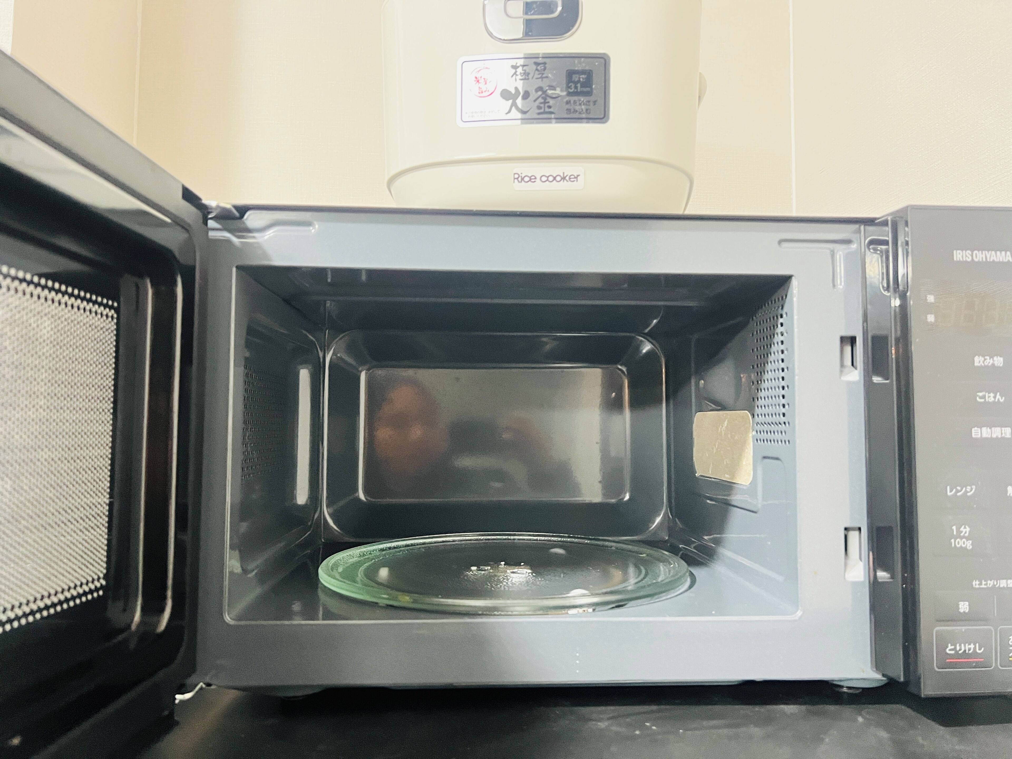 Un four à micro-ondes ouvert, avec une assiette en verre à l’intérieur.