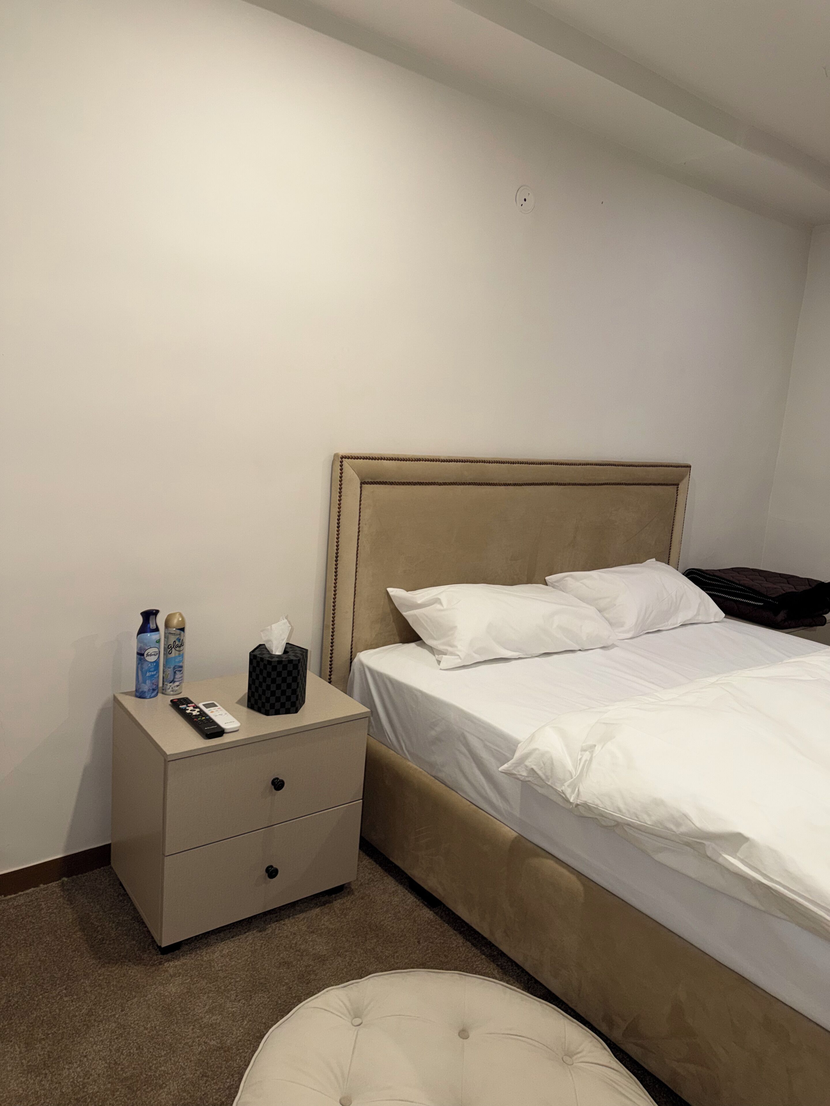 Ein Hotelzimmer mit Bett, Nachttisch, Fernbedienung und Pflegeprodukten.