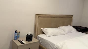 Ein Hotelzimmer mit Bett, Nachttisch, Fernbedienung und Pflegeprodukten.