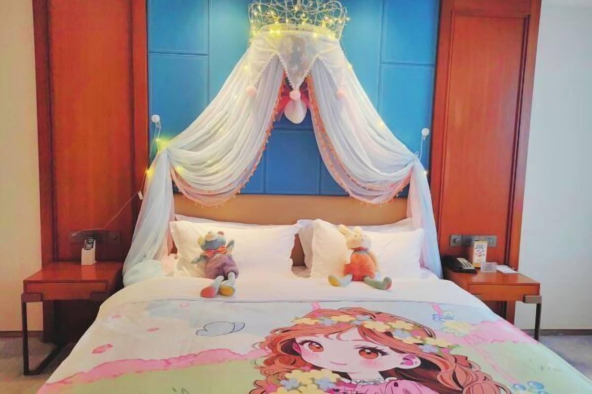 Un dormitorio con cama con dosel, juguetes suaves y un personaje de caricatura en la colcha.