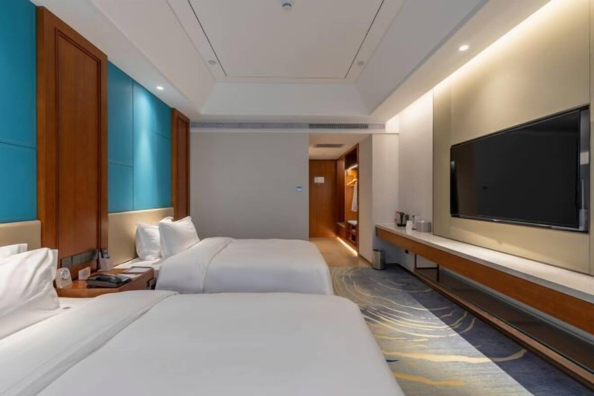 Habitación de hotel con dos camas, un televisor de pantalla plana grande y piso alfombrado.