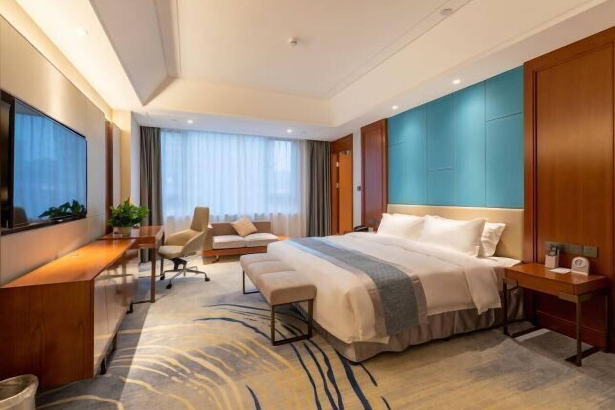 Habitación de hotel moderna con una cama grande, un escritorio, una silla y un televisor.