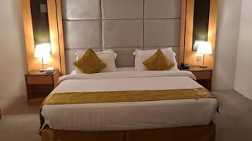 A hotel room with a large bed, two bedside tables with lamps, and a padded headboard.