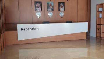 A reception desk with a sign, wooden paneling, and framed photographs on the wall.