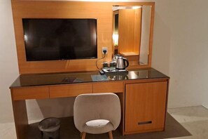 A hotel room with a wooden desk, a television, a mirror, and a chair. - Al Rayyan Tower (Jeddah)