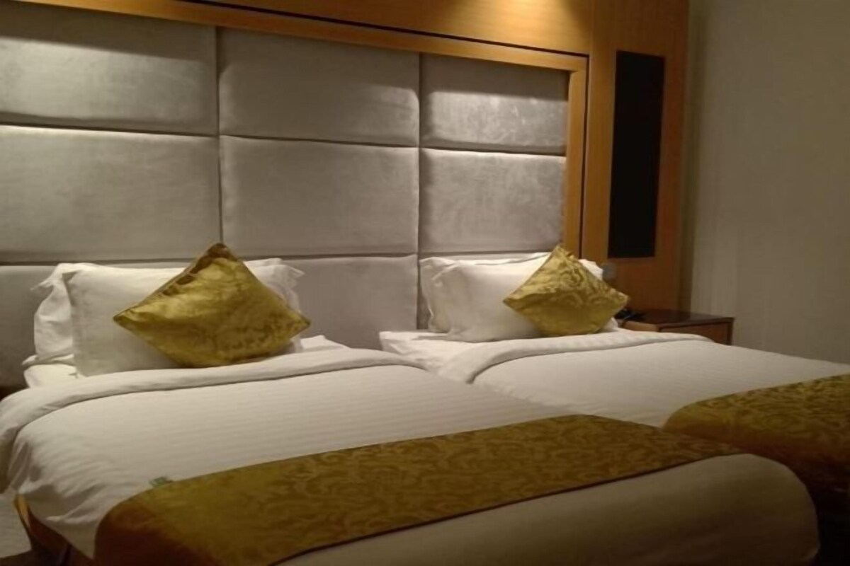 A hotel room with a large bed, two pillows, and a headboard.