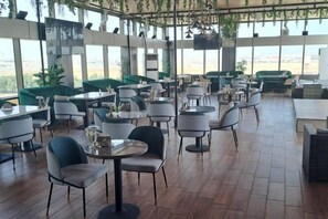 A restaurant with multiple tables and chairs, large windows, and a view of the outdoors. - Al Rayyan Tower (Jeddah)