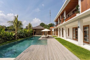 Ein modernes Resort mit Schwimmbad, Holzterrasse und üppiger Bepflanzung.