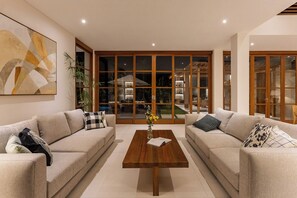 Ein modernes Wohnzimmer mit zwei beigefarbenen Sofas, einem Holztisch und einem großen abstrakten Gemälde an der Wand.
