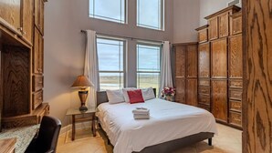 A bedroom with a large bed, wooden wardrobe, and a desk with a lamp. - 8BR Ranch house perfect for large families/groups (Rosharon)