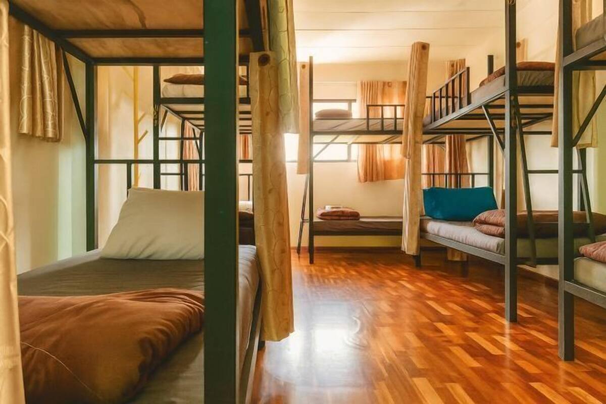 Un dormitorio con literas, suelo de madera y cortinas.
