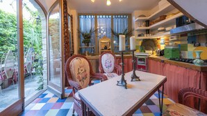 Une cuisine avec un coin repas, de grandes fenêtres et un sol aux couleurs vives.