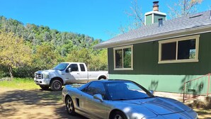 A silver sports car parked in front of a house with a green exterior and a chimney. - Waterfront 3-bedroom house in Clearlake Park with private dock (Clearlake Park)