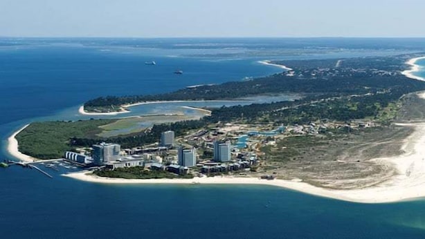 An aerial view of a coastal resort with beachfront properties, a marina, and a small island with dense vegetation. - GuestReady - Insígnia Troia apartment (Praia de Troia)