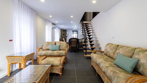 A spacious living area with a sofa, chairs, a table, and a staircase. - GuestReady - beachfront retreat in Porto Formoso (Porto Formoso)