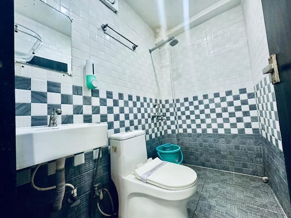 Une salle de bain avec des toilettes blanches, un lavabo et un espace douche.