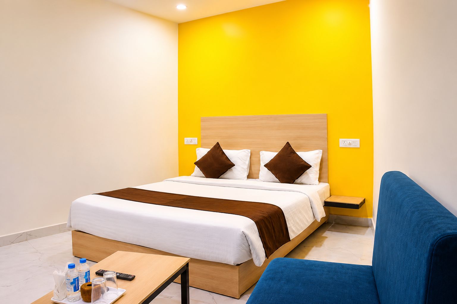 A hotel room with a bed, bedside table, and a blue armchair.