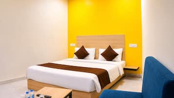A hotel room with a bed, bedside table, and a blue armchair.