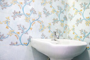 Ein Badezimmer mit einem weißen Waschbecken und einer Wand mit floralem Dekor.