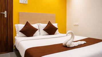 Habitación de hotel con cama, almohadas marrones, decoración de cisne blanco, cabecera de madera y pared amarilla.