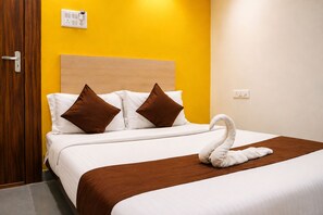 A hotel room with a bed, brown pillows, a white swan decoration, a wooden headboard, and a yellow wall. - Kanha Inn (Bhopal)
