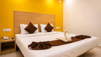 A hotel room with a bed, a nightstand, a telephone, and a swan-shaped towel.